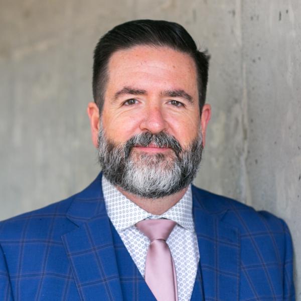 Grant McMillan standing in front of grey wall