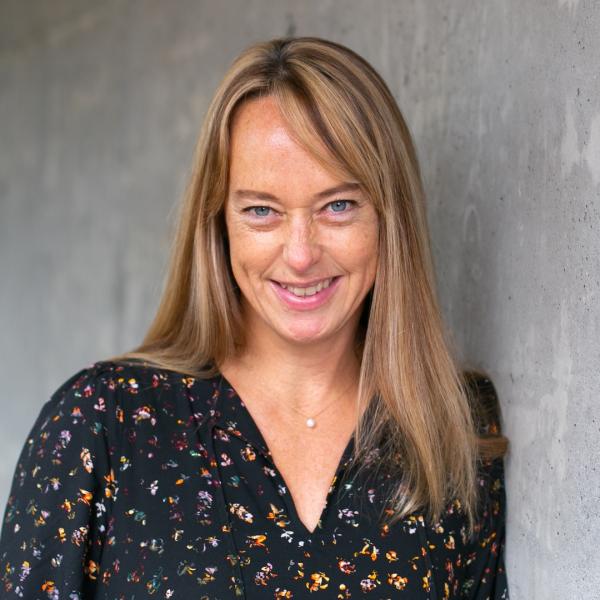 Kathy Holmes standing in front of grey wall