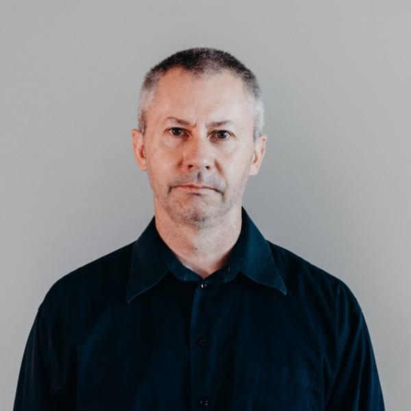 Dr. Steve Nicolle wearing black shirt against gray background.