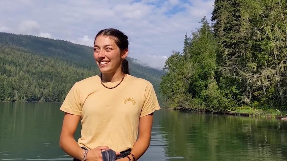woman standing in front of a lake and smiling