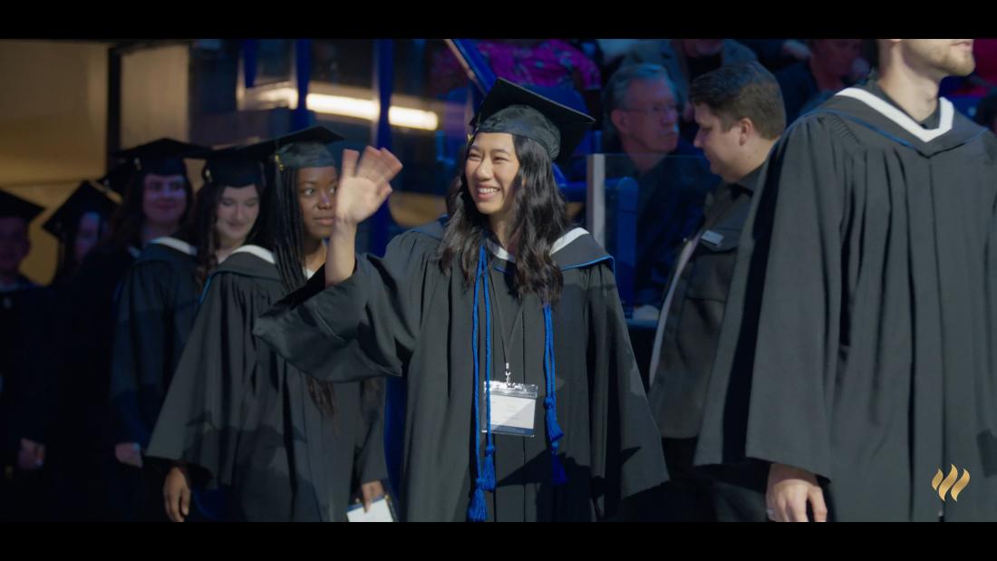Graduate waving in their cap and gown