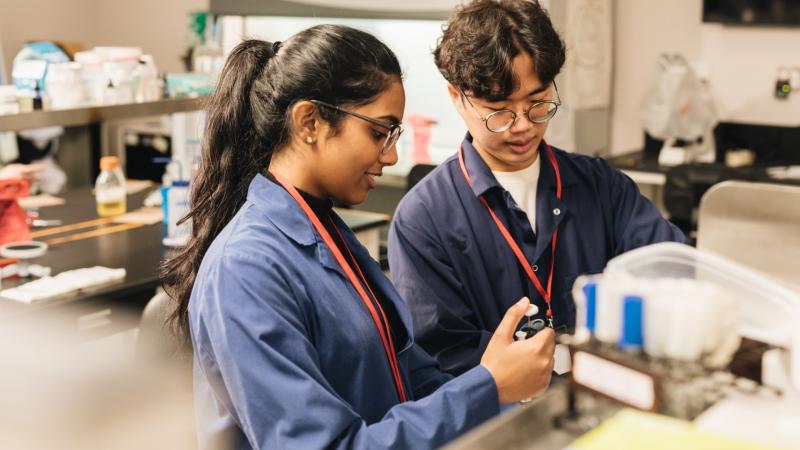 Two students in a lab looking at a machine