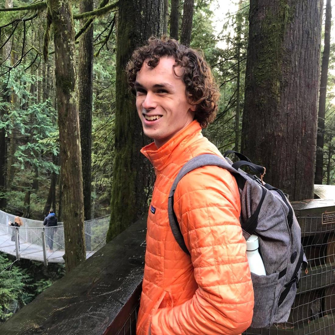 student on a bridge smiling at the camera