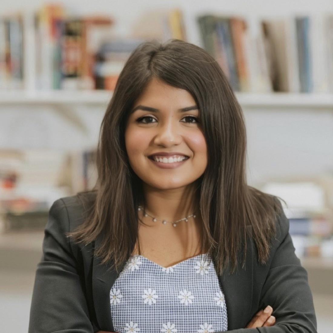 Candice DCruz standing in front of a bookshelf smiling