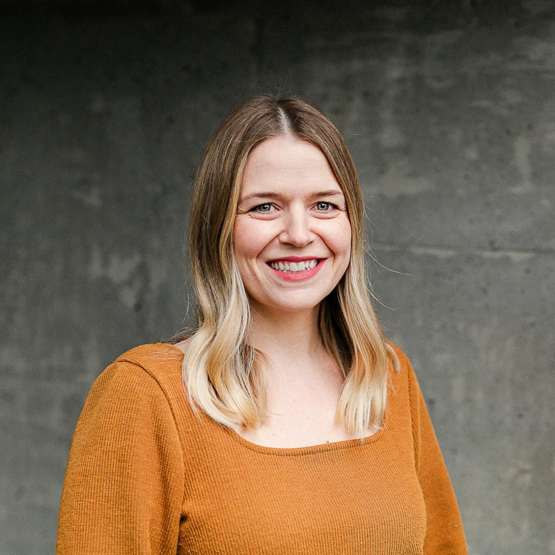 Stephanie Beugelink standing in front of grey wall