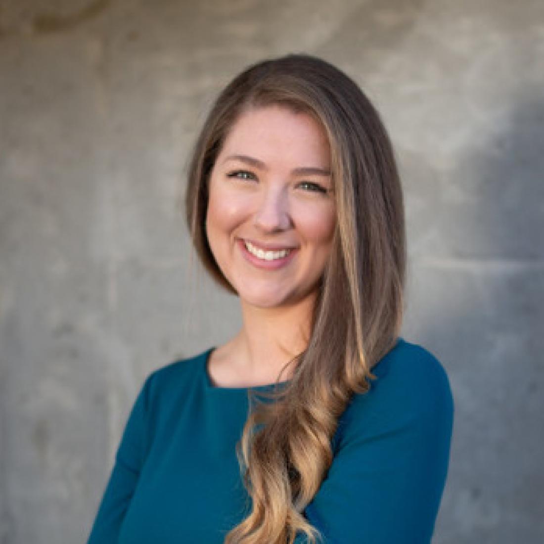 Bethany Erickson standing in front of a grey wall smiling