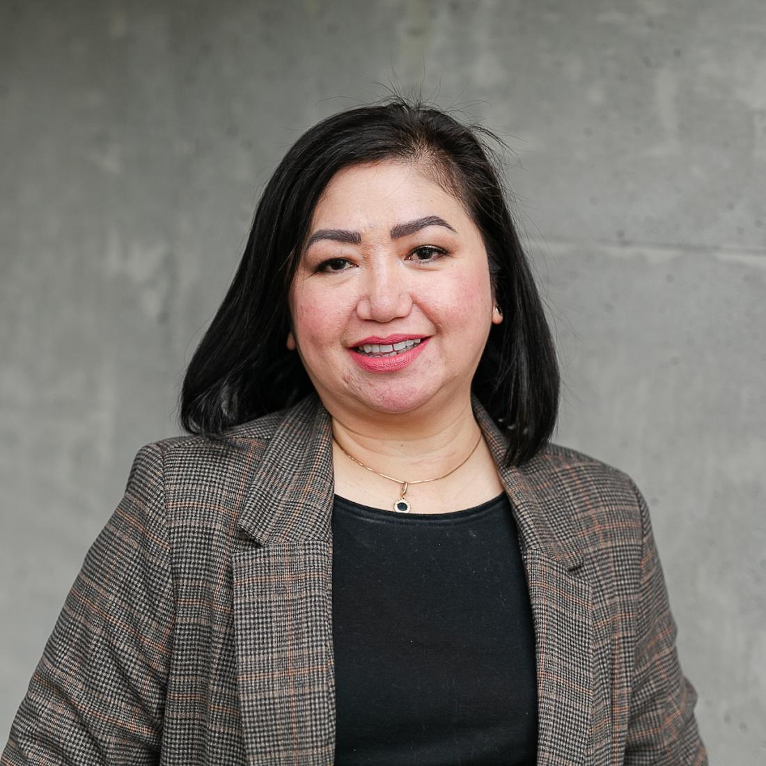 Eleonor Mendoza standing in front of a grey wall