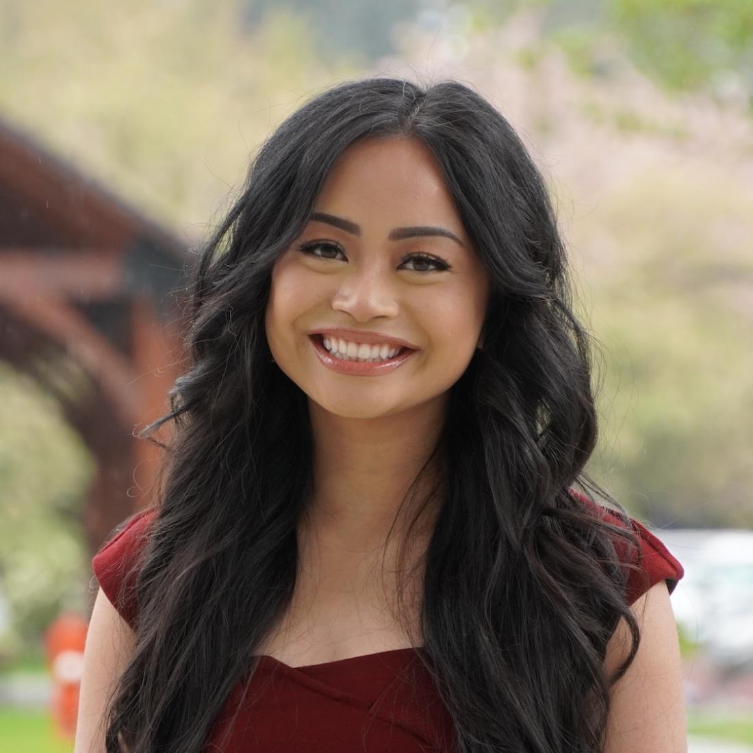 Women with black hair smiling at the camera in front a green background with the wood structure in the background