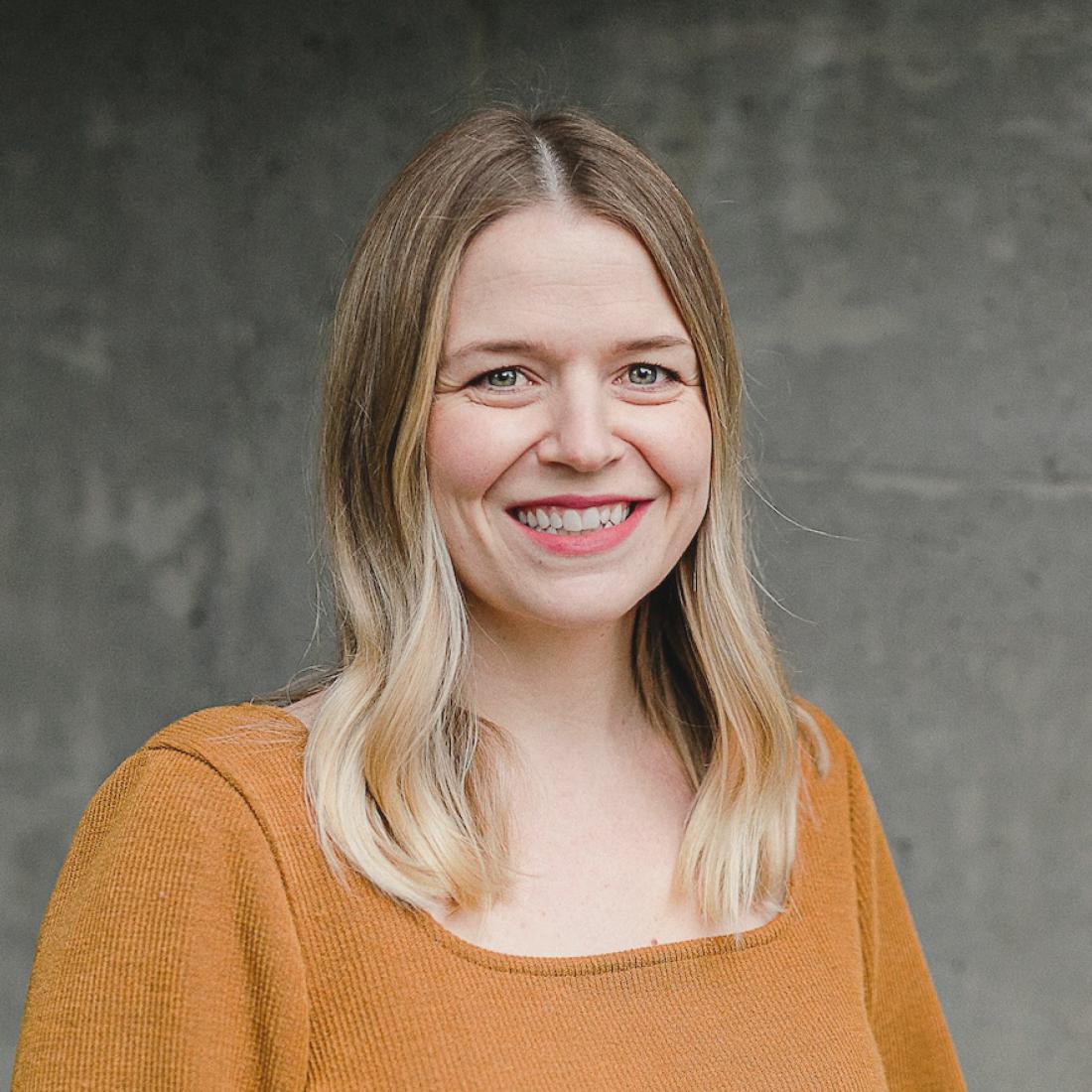 Stephanie Beugelink standing in front of grey wall