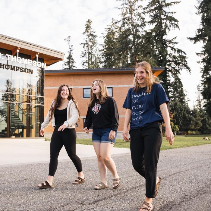 Three students happily walking past Robert N. Thompson