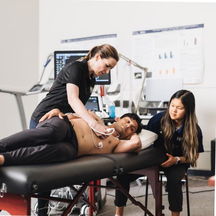 Professor teaching student with live patient on table