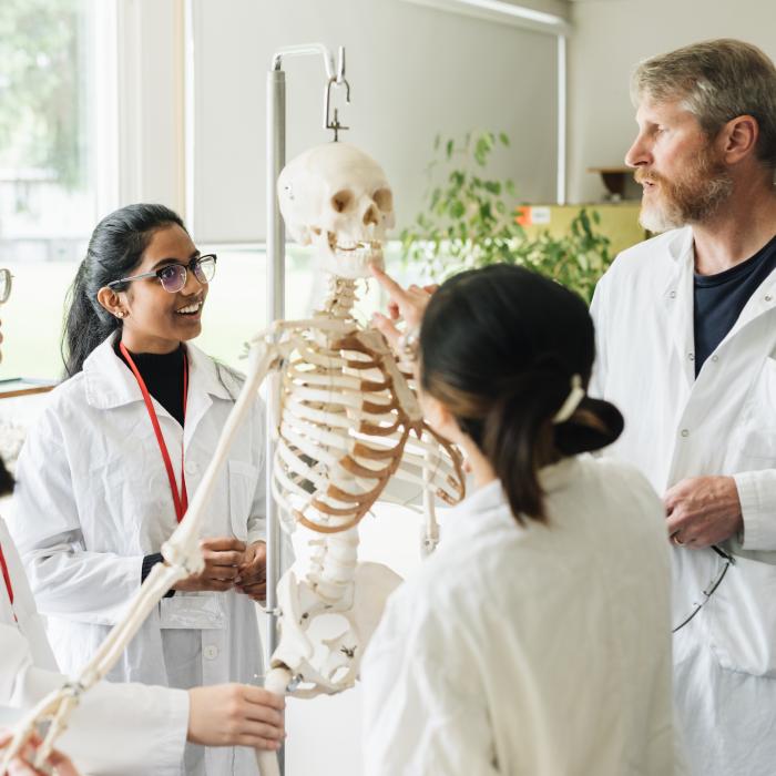Students in class with professor looking at a skeleton