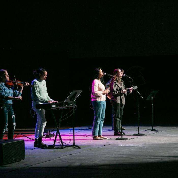 TWU's chapel worship band on stage in the gym. There are instruments and purple lights.