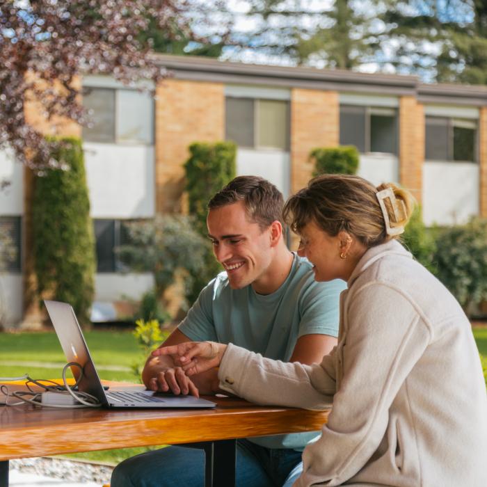 Students looking at laptop outdoors