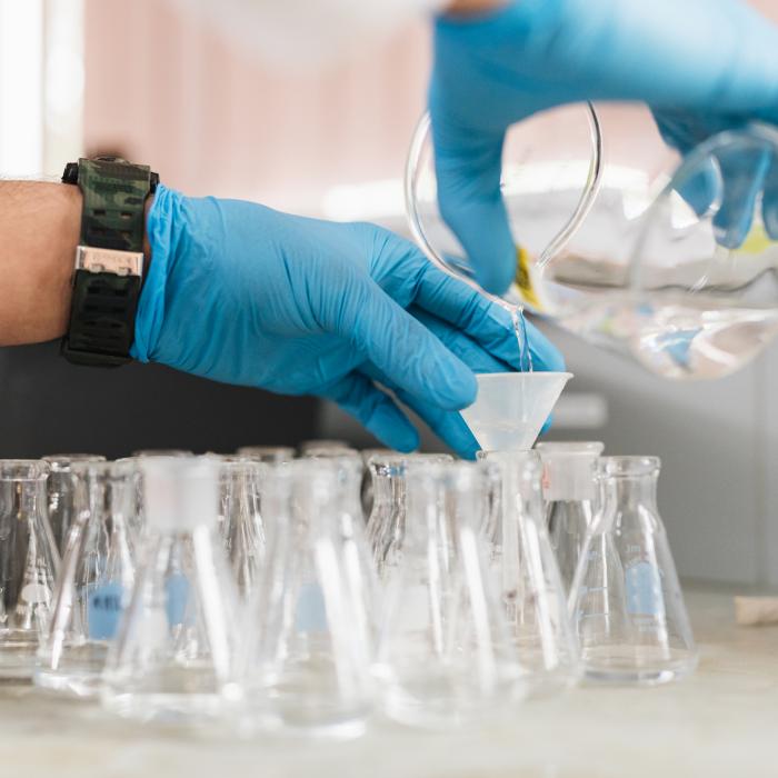 Hands pouring into a beaker