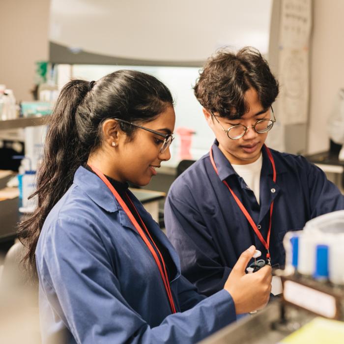 Two students in a lab looking at a machine