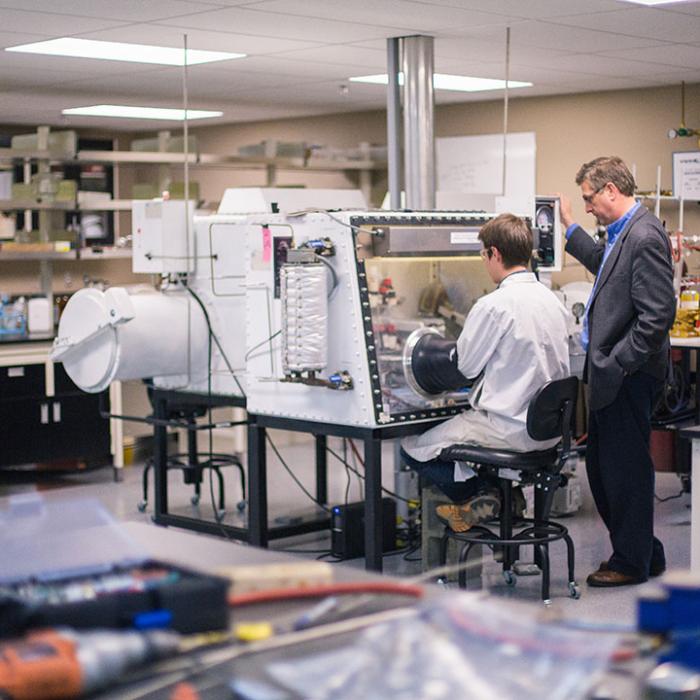 Research lab with student using a machine and professor instructing