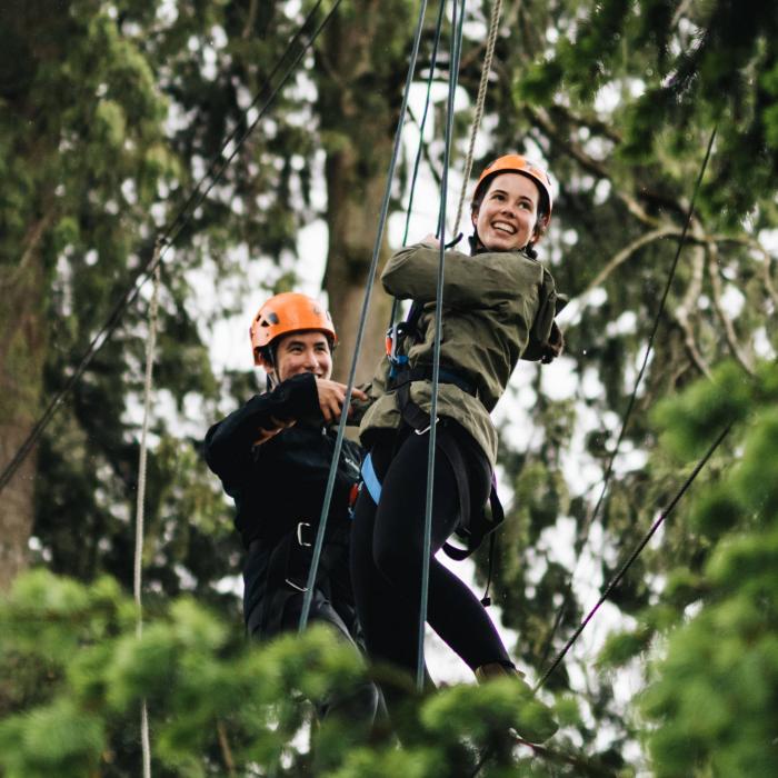 two people on high ropes in trees