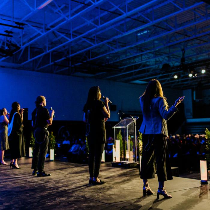 people standing on stage in gym signing