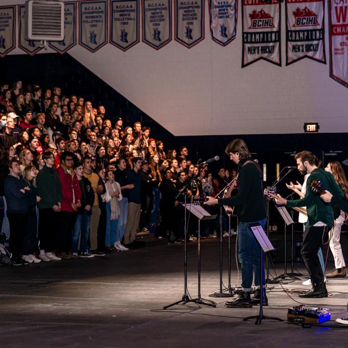 people in bleachers of gym with band playing music