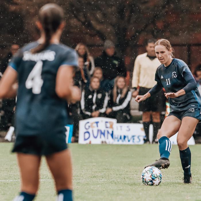 women playing soccer in the rain