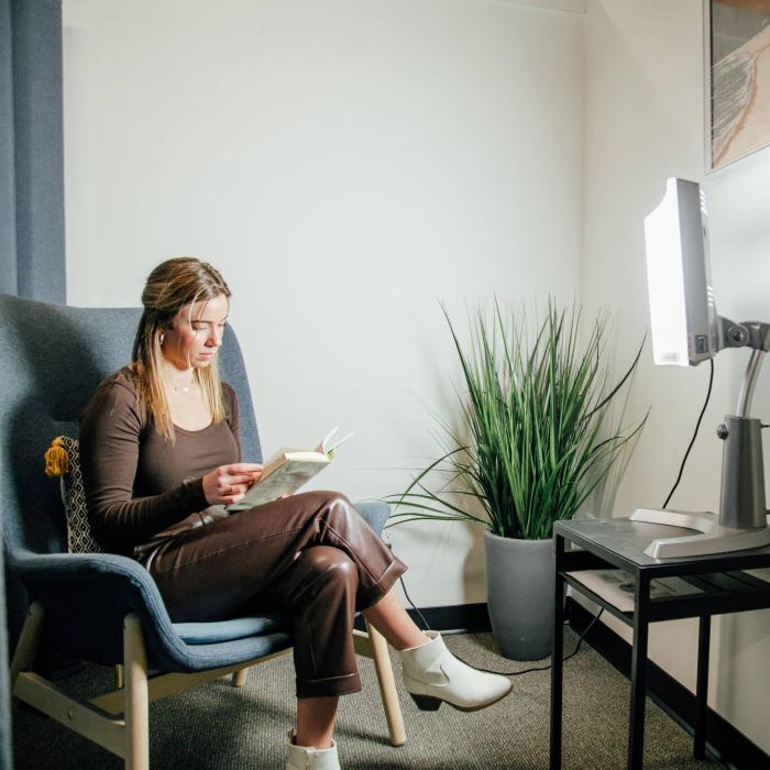 young woman reading a book in front of sunlight lamp