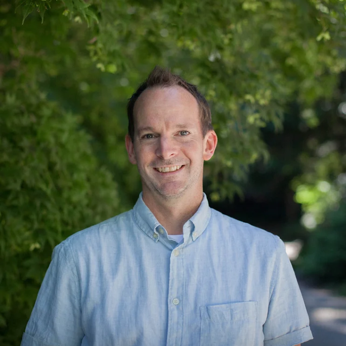 Mark Walters standing in front of trees in a blue collared shirt