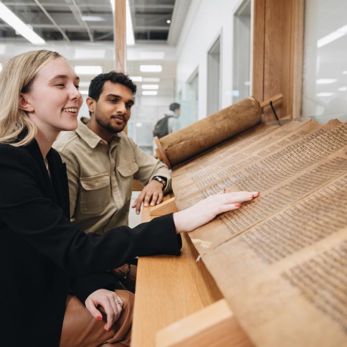 smiling students interacting with Torah scrolls