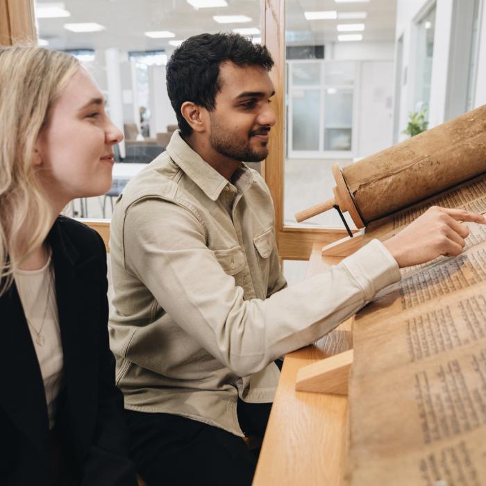 two students engaging with biblical scrolls