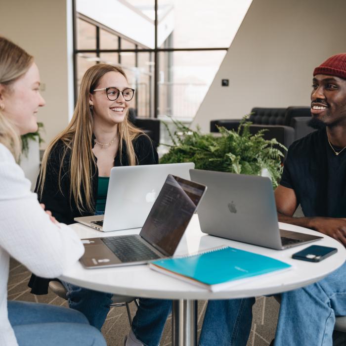 three students enjoying their conversation at a table