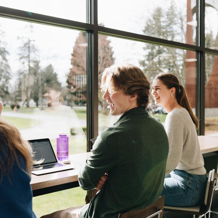 three students seated facing the window and enjoying a discussion