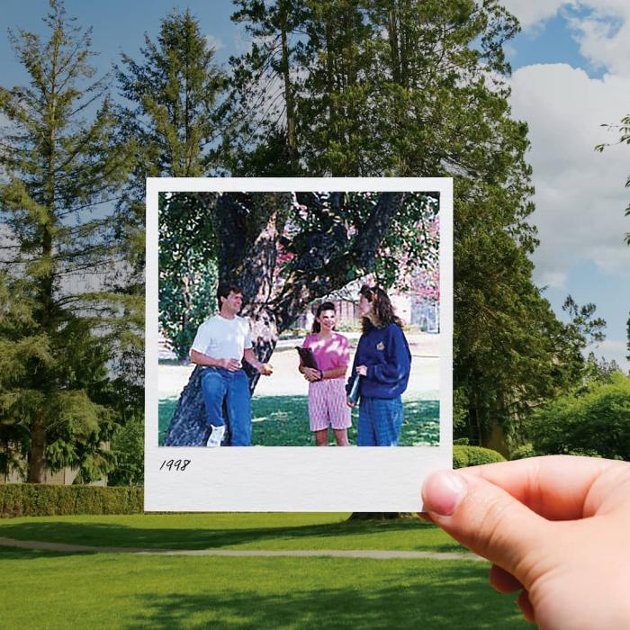 persons hand holding a Polaroid photo outside in front of tree