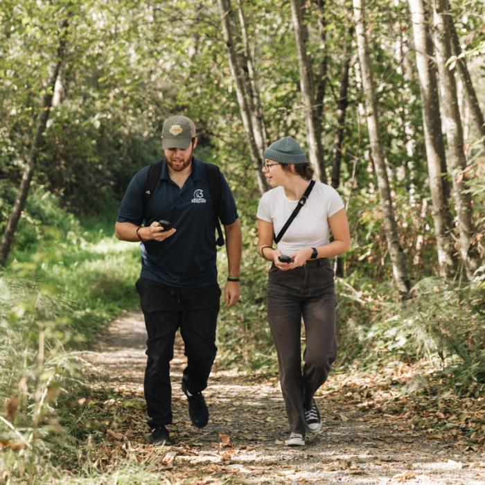 students walking through forest looking at equipment