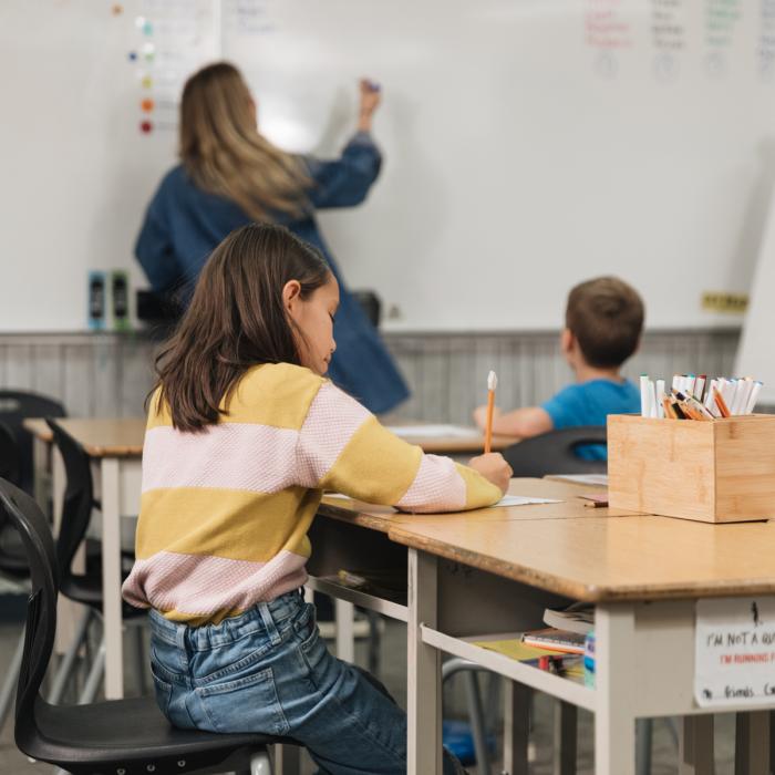 teacher teaching young children in a classroom using a whiteboard