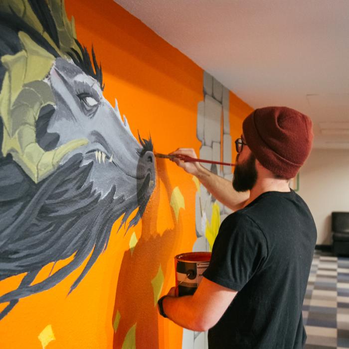 student painting dragon mural