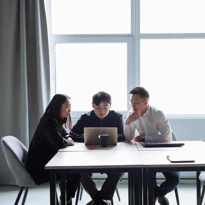 three students working on a laptop