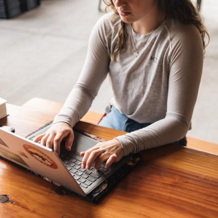 woman using laptop outdoors on wooden table