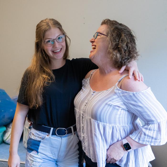 mother and daughter smiling with their arms around each other