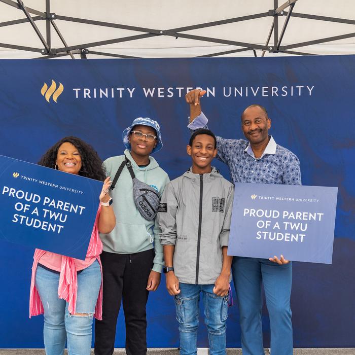 TWU parents holding signs and smiling with their students