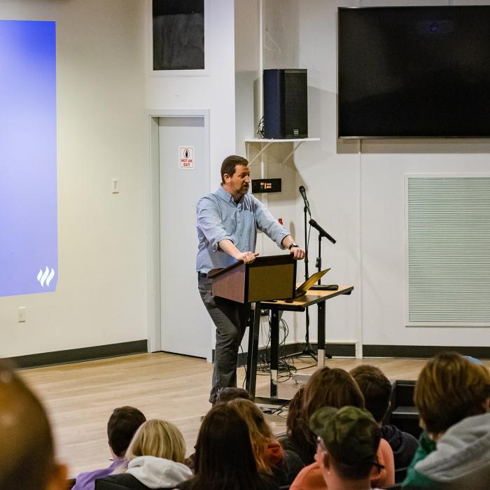Kevin Schut talking to a group of people in auditorium 