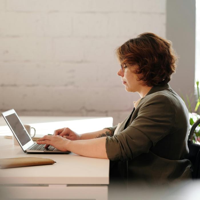 women in a wheelchair sitting at desk and working on a laptop