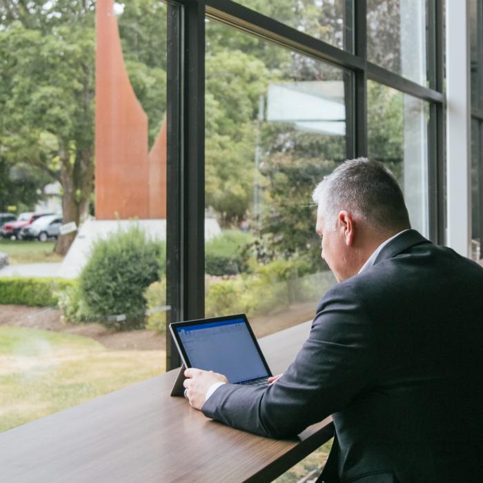 man working on computer in front of large windows