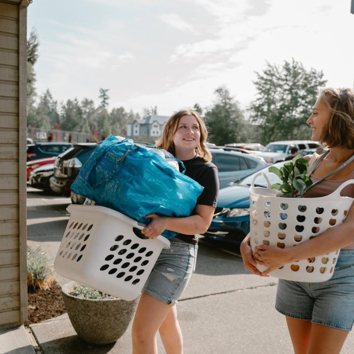 students holding baskets of belongings to move in to dorms