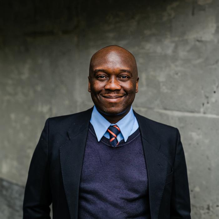 Christopher Ogundare standing in front of grey wall