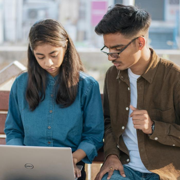 women with laptop and man sitting on bench outside