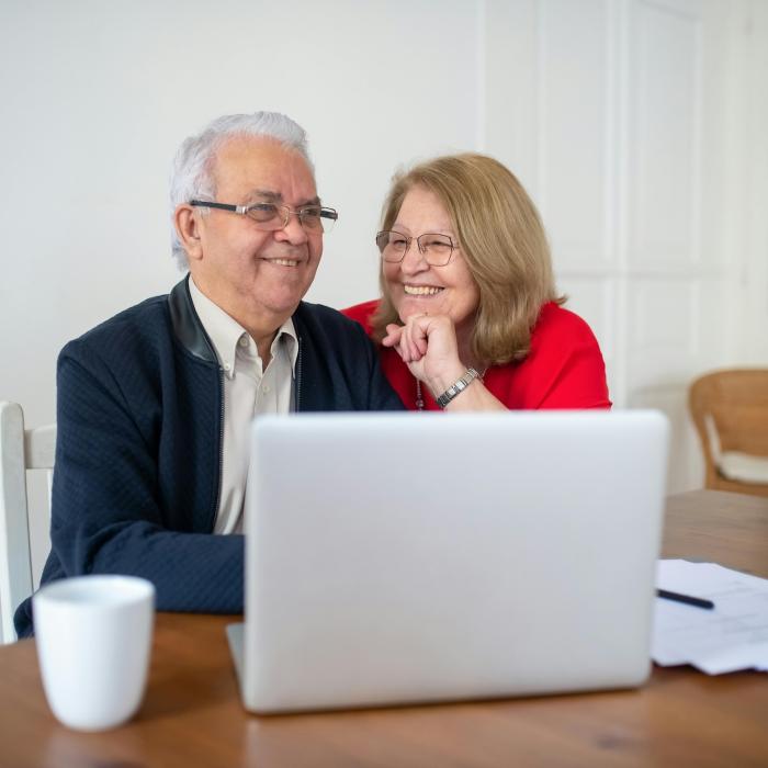 older couple sitting at table with laptop