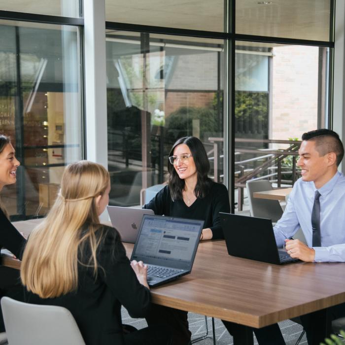 Four people sitting at a desk working or talking