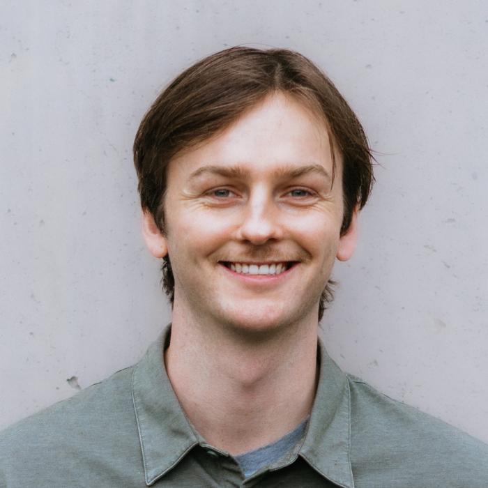 A photo of Jack Derrenbacker wearing a gray shirt and smiling
