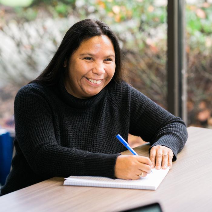 Woman sitting at a desk, taking notes.