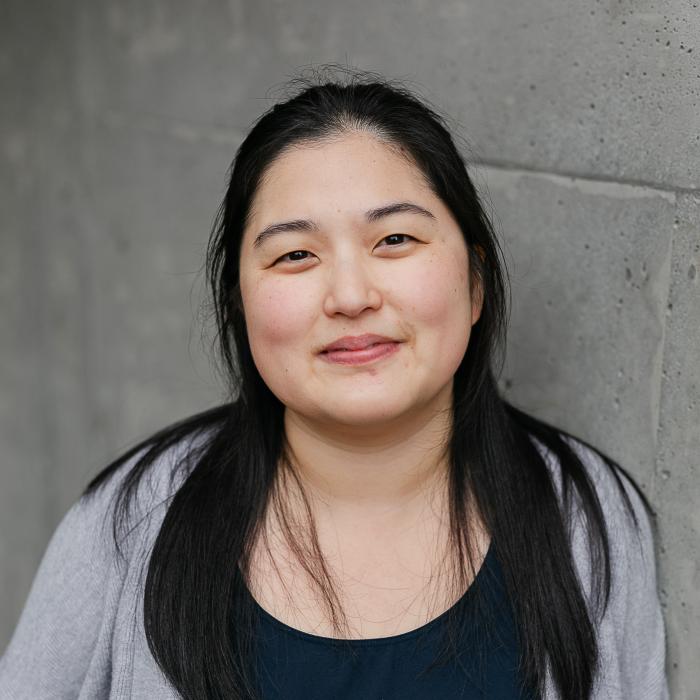A photo of Jina Joo in front of a concrete wall